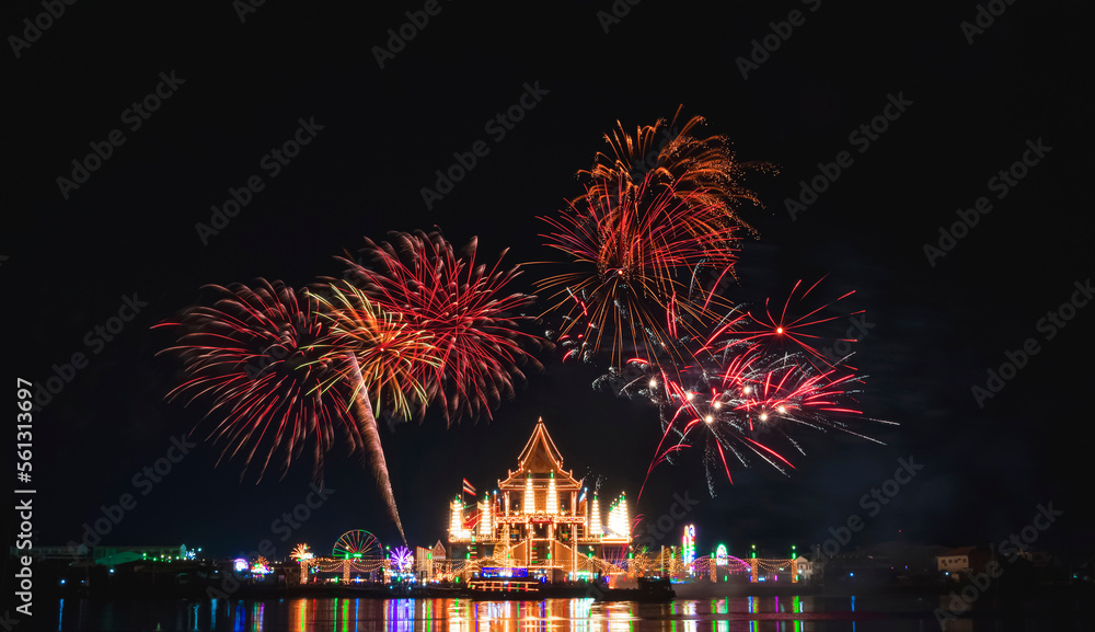 Beautiful fireworks in night sky over Wat Krok Krak Thai temple with decorative lighting and light reflection on river surface in annual festival area at night in Samutsakhon, Thailand - obrazy, fototapety, plakaty 