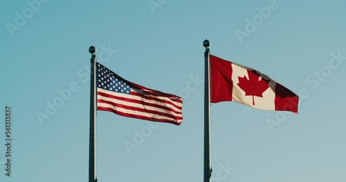 American and Canadian flags flutter in the wind against the sunset sky. U.S.A Flag and flag of Canada stand together the wind flutters the flags against the background of a beautiful blue sky. photo