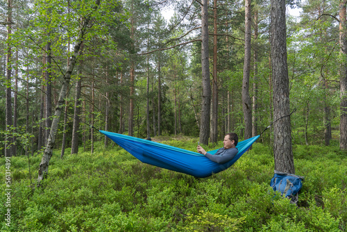 Man using his mobile phone while relaxing in hammock.