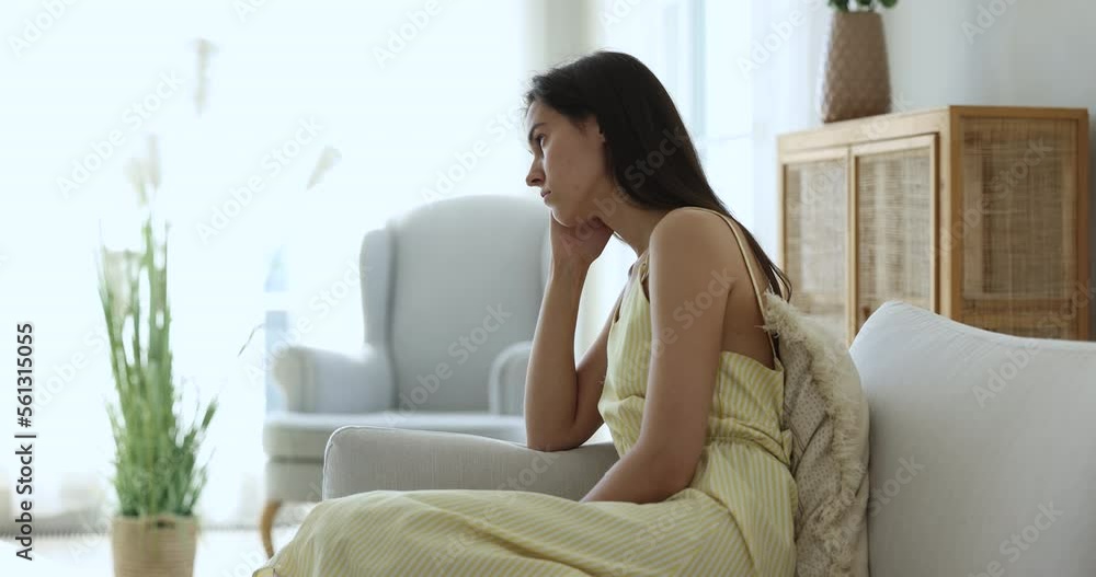 Young sad pensive female reflecting, suffers of loneliness, depression or boredom alone at home, feels fatigued resting seated on sofa staring into distance looks thoughtful, ponders, deep in thoughts Young sad pensive female reflecting, suffers of loneliness, depression or boredom alone at home, feels fatigued resting seated on sofa staring into distance looks thoughtful, ponders, deep in thoughts