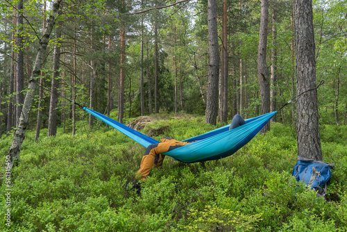 Hiker sleeping in a hammock between trees.