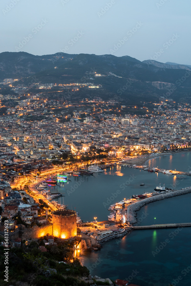 Fototapeta premium Beautiful portrait of Alanya Harbour and the Red Tower at night with the Taurus Mountains and Mediterranean Sea, Turkey.