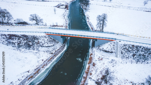 Winter landscape. Aerial view of the bridge over the river. Pieces of the ice on the water.