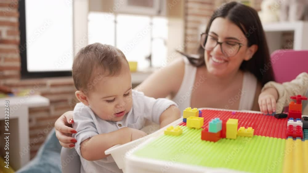 Teacher with boys playing with construction blocks sitting on table at kindergarten Teacher with boys playing with construction blocks sitting on table at kindergarten