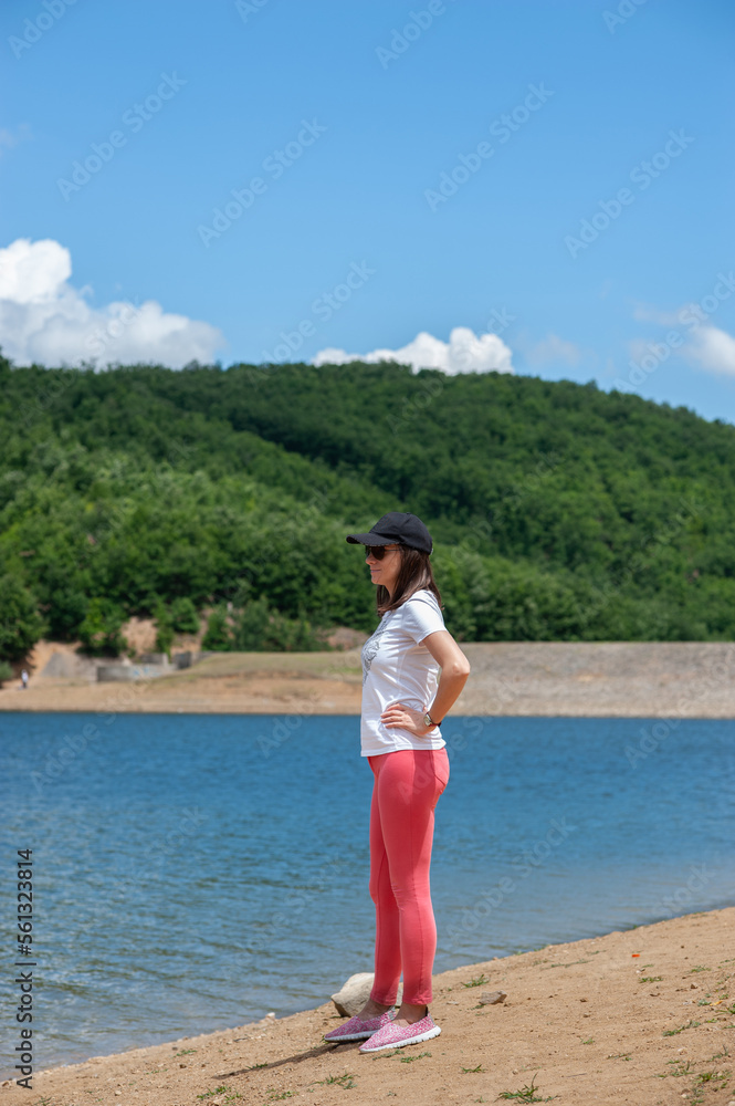 A young woman is standing by the lake