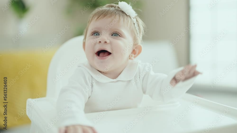Adorable blonde baby smiling confident sitting on highchair at home Adorable blonde baby smiling confident sitting on highchair at home