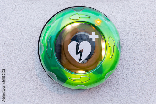 green lit Automated External Defibrillator, AED on a white wall