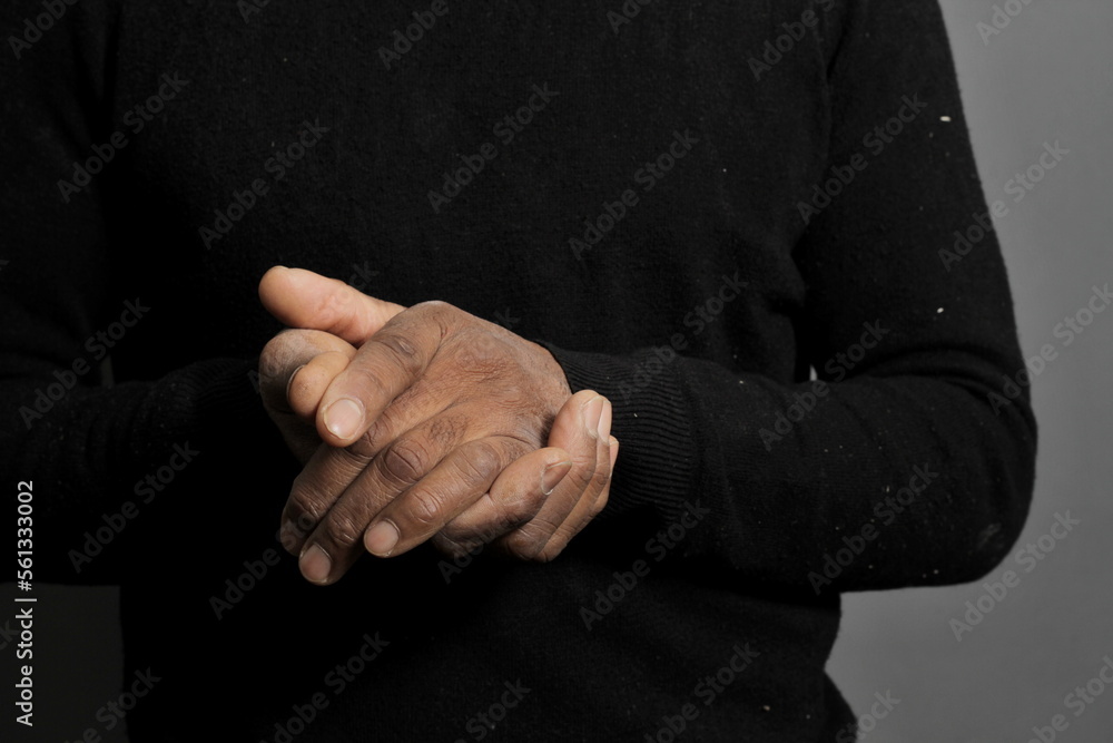 Fototapeta premium man praying to god with hands together Caribbean man praying on grey black background with people stock photo