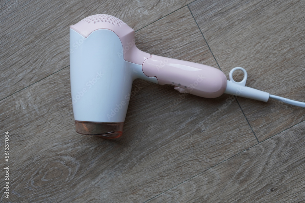 Fototapeta premium top view white and pink plastic hair dryer on wooden floor background, object, technology, decor, copy space