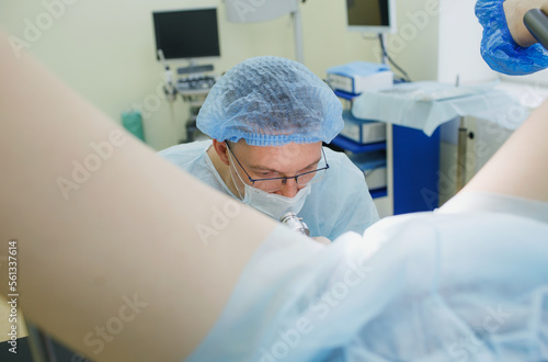 Canvastavla a proctologist examines a rectal colonoscopy patient lying on a medical chair in the surgical office