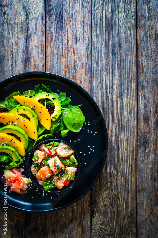 Salmon ceviche with lemon, mango and avocado on wooden table
Salmon ceviche with lemon, mango and avocado on wooden table