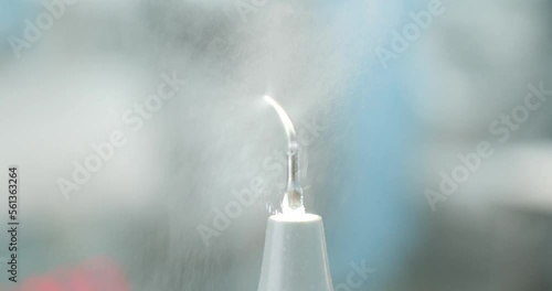 Dental ultrasonic scaler close-up sprays small drops of water. Oral scaler for removing plaque and calculus from teeth in the process. Close-up of the tip of a dental scaler.