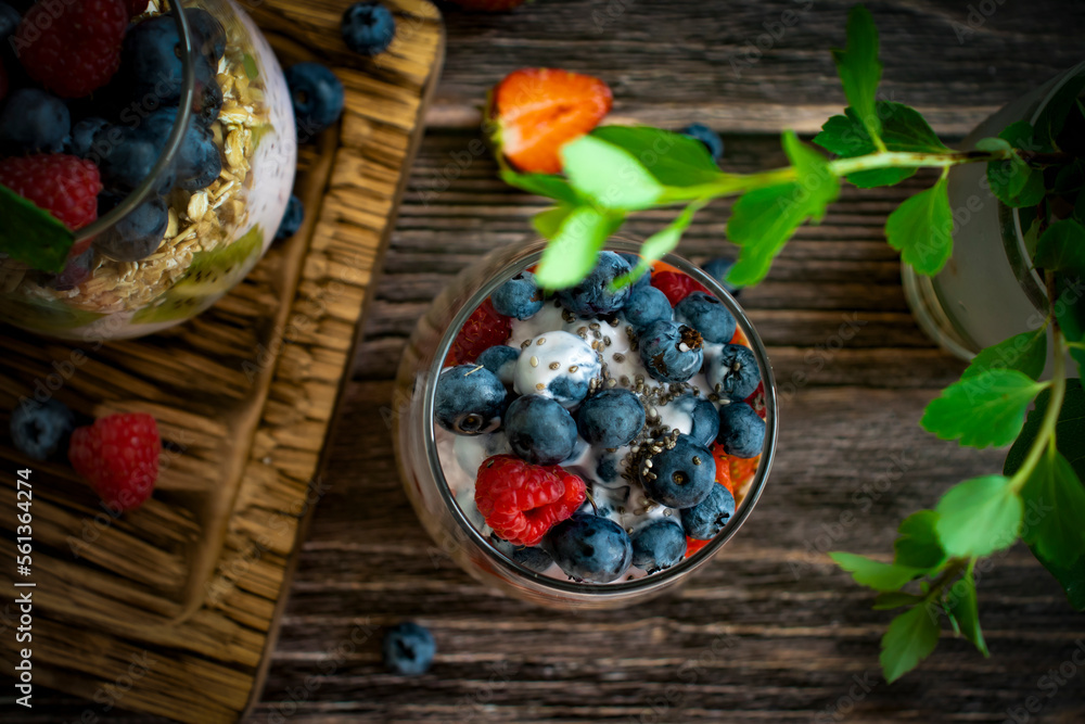 Yogurt, chia seeds, blueberries, strawberries, raspberries, mint, kiwi on a dark background