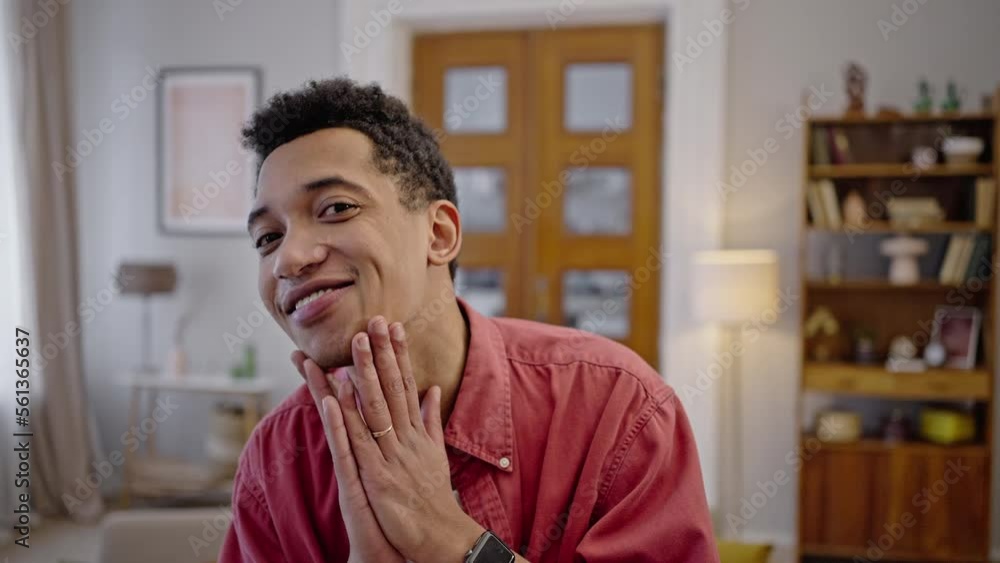 Young African man looks at camera as in mirror, fixes hair and strokes chin, enjoys his appearence Young African man looks at camera as in mirror, fixes hair and strokes chin, enjoys his appearence