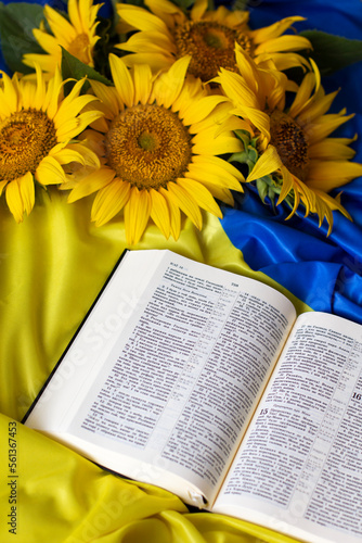 Bible (Holy Writ) and sunflowers on background of flag of Ukraine.