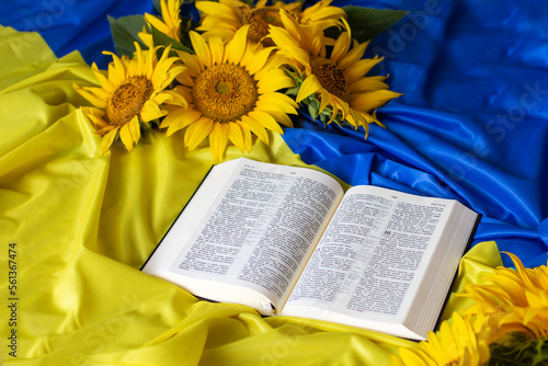 Bible (Holy Writ) and sunflowers on background of flag of Ukraine.