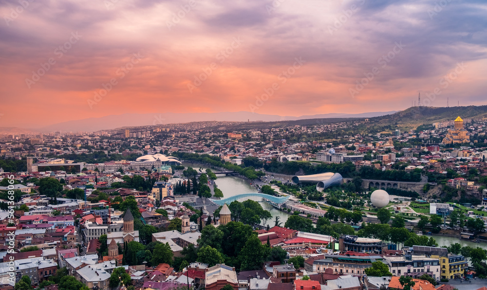 Old Tbilisi cityscape with Mtkvari or Kura river, Cathedral, bridge of peace, Rike park and presidential palace at sunset with dramatic sky. Tiflis is popular tourist destination in Georgia
