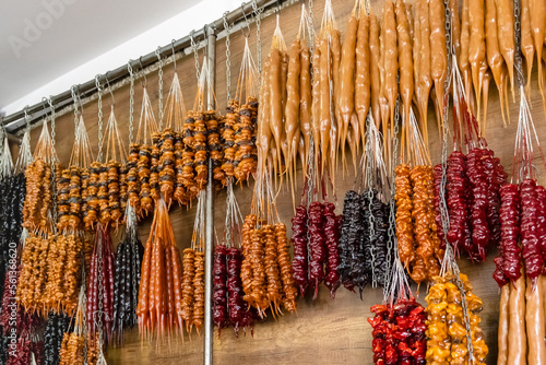 Churchkhela - traditional Georgian homemade sweets with different nuts, dried fruits, flour and grape juice or must. Bunches of national dessert hanging at local food market or shop in Georgia photo