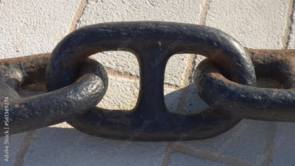 Iron chain - series of metal stud links. Heavy steel anchor bond, black with some rust, on white stone tiles. Iron chain - series of metal stud links. Heavy steel anchor bond, black with some rust, on white stone tiles.