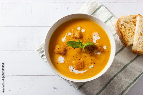 Cream of pumpkin and carrot soup on a rustic wooden background. Top view. Copy space.