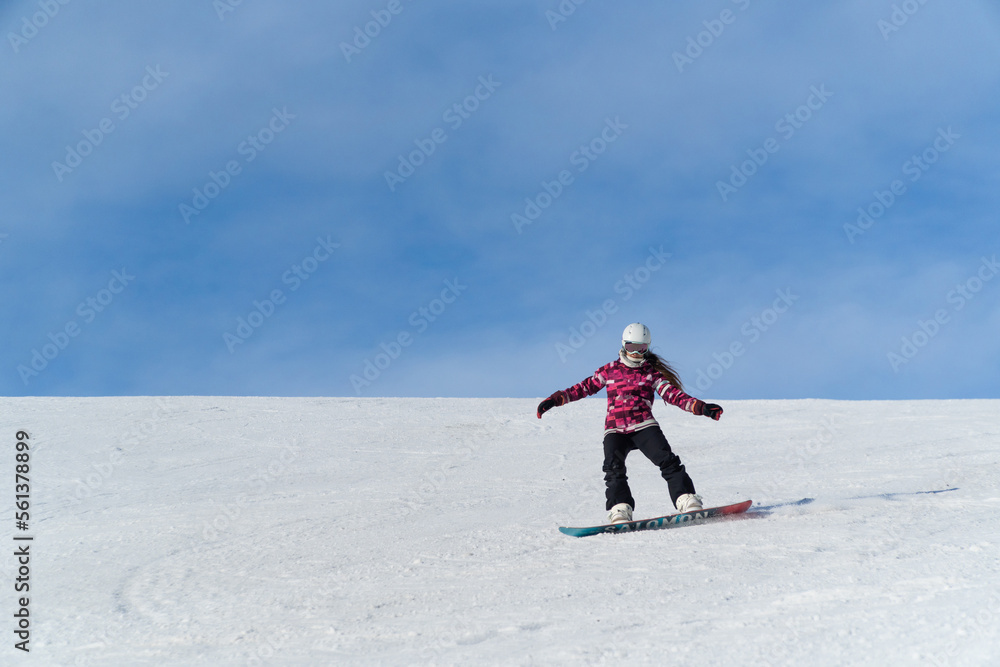 Girl snowboarding in the snow on the mountain on a sunny day