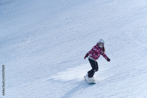 Girl snowboarding in the snow on the mountain on a sunny day