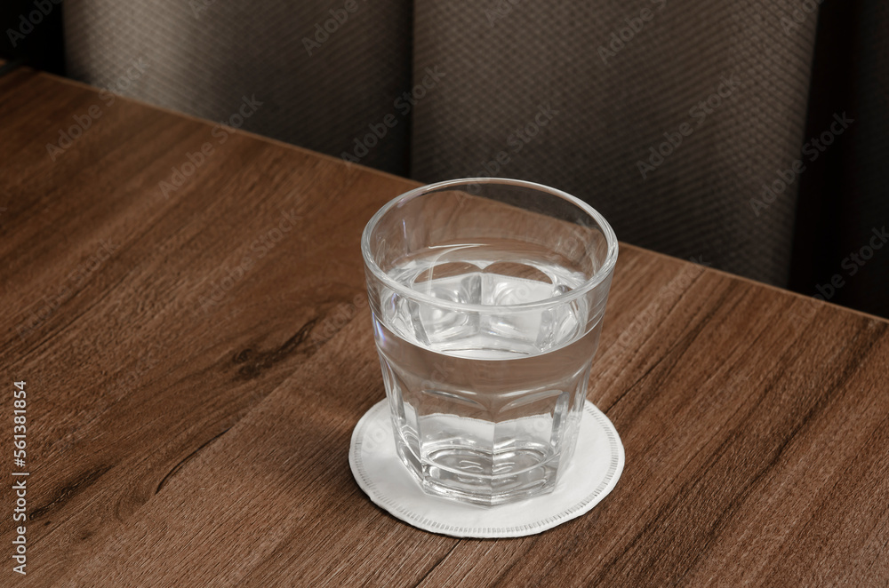 A glass of water on a wooden table. Clean clear water for drinking. A glass of water on a wooden table. Clean clear water for drinking.