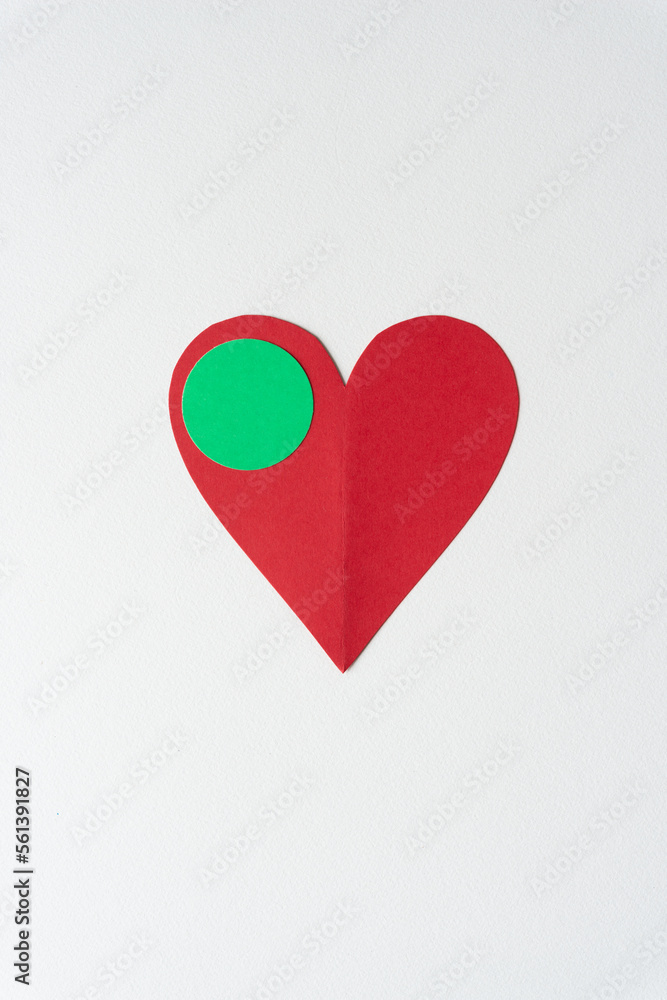 red paper heart with slight crease and green dot