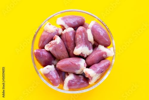 Chicken hearts in glass bowl on yellow background.