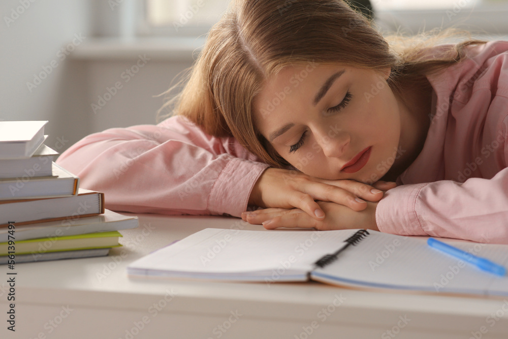 Young tired woman sleeping near books at white table indoors Young tired woman sleeping near books at white table indoors