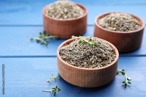 Bowls with dried and fresh thyme on blue wooden table  closeup