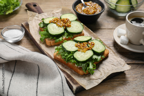 Tasty cucumber sandwiches with arugula, mustard and coffee on wooden table