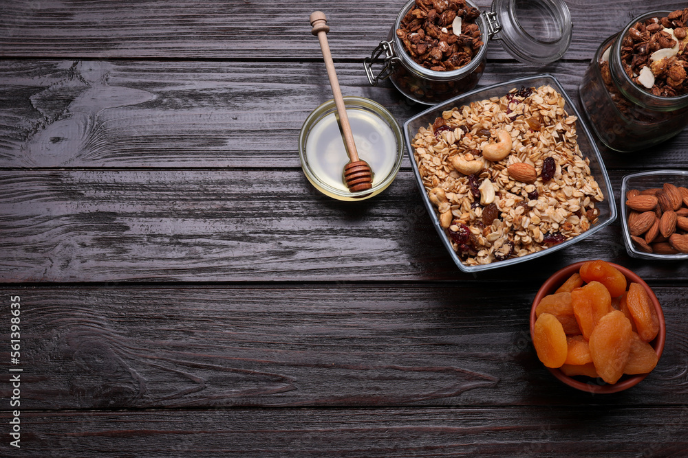 Fototapeta premium Tasty granola served with nuts and dry fruits on wooden table, flat lay. Space for text