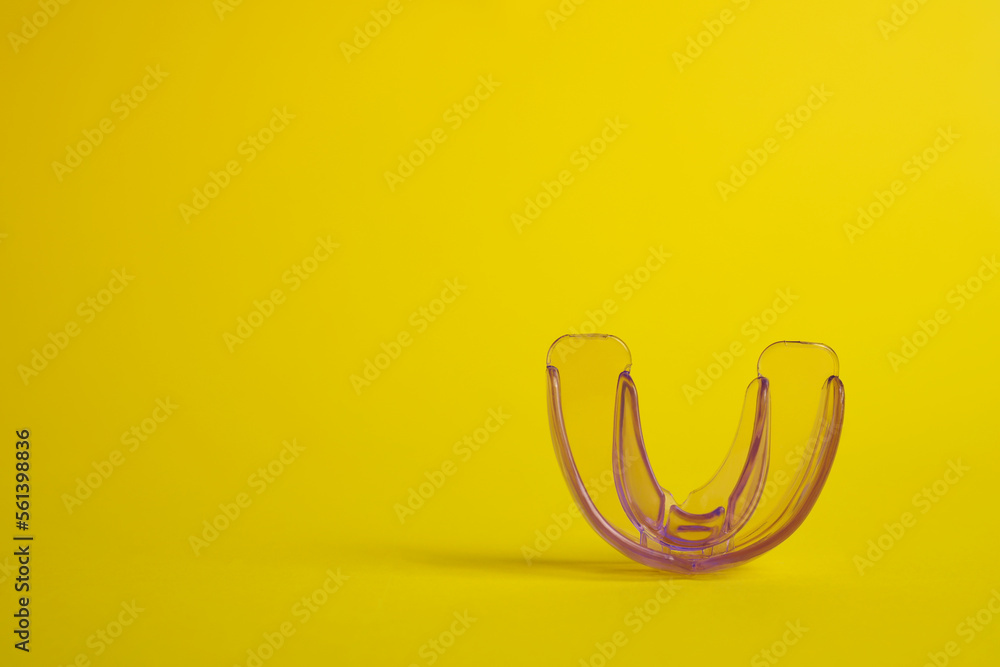 Fototapeta premium Transparent dental mouth guard on yellow background, space for text. Bite correction