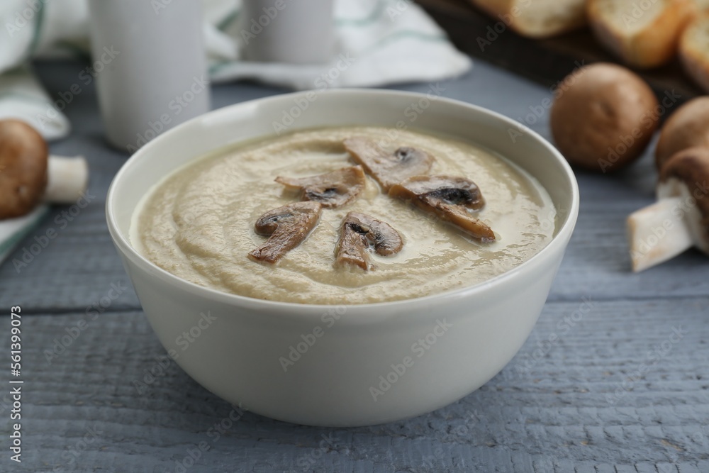 Delicious mushroom cream soup on light grey wooden table, closeup Delicious mushroom cream soup on light grey wooden table, closeup