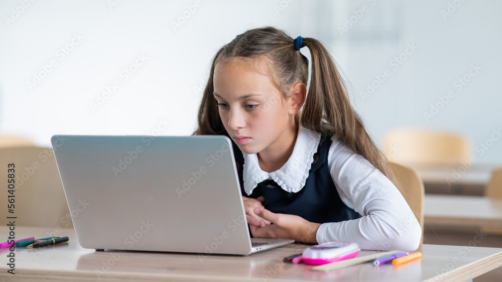 Caucasian girl studying on a laptop in a classroom. Caucasian girl studying on a laptop in a classroom.