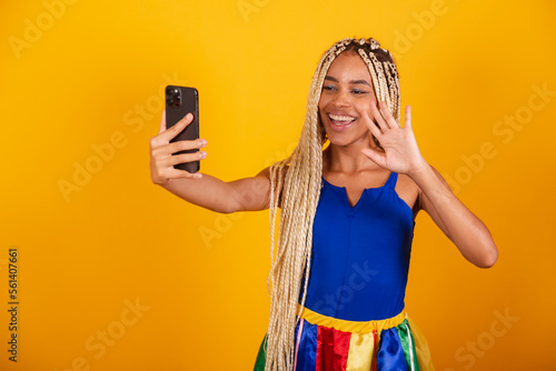 beautiful black, brazilian woman with braids, wearing clothes for carnival. Holding smartphone. self Portrait. photo