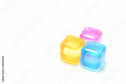 Cubos de hielo de colores sobre aislados en un fondo blanco. Espacio para texto al lado izquierdo.