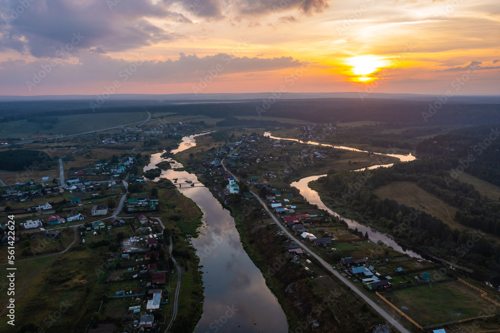 panoramic view of the Russian village with a flooded river and rapids , country road on the shore a bird's-eye view from a drone at sunset in the golden hour with purple clouds and the sun