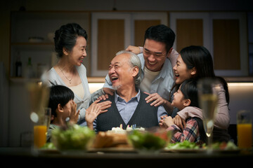 three generation asian family celebrating grandpa's birthday at home