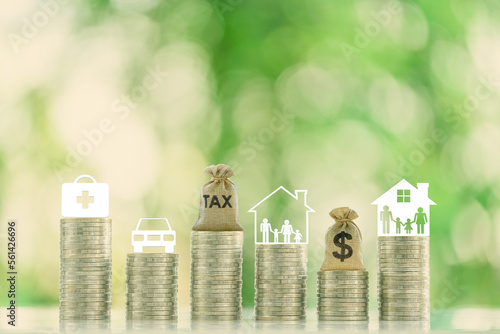 Family tax benefit, inherit tax, property or estate and household tax concept : Tax bag, family with kids living in a residential facility, a dollar bag, a car, a first aid kit are atop coin stacks.