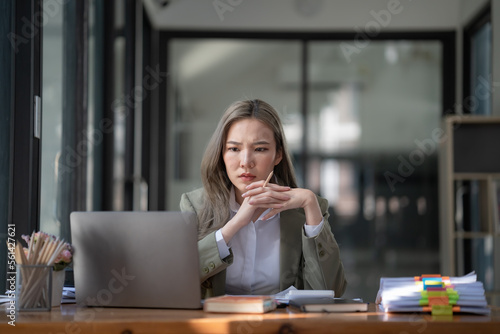 Asian woman thinking hard concerned about online problem solution looking at laptop screen, worried serious Asian businesswoman focused on solving difficult work computer task.