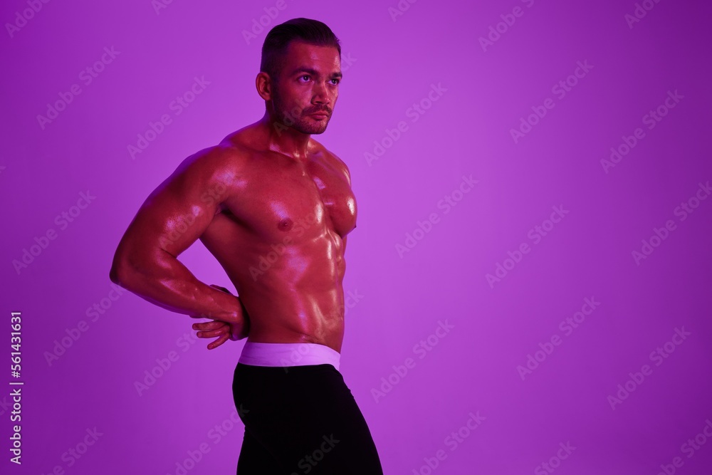 Fototapeta premium Man athletic body bodybuilder in briefs with nude torso abs full-length in the background fitness classes, purple colored light. Advertising, sports, active lifestyle, competition, challenge concept.