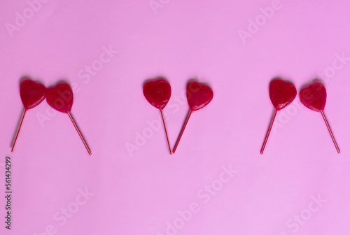 valentine background. heart shaped lollipops distributed in a line on a pink background leaving free space for text