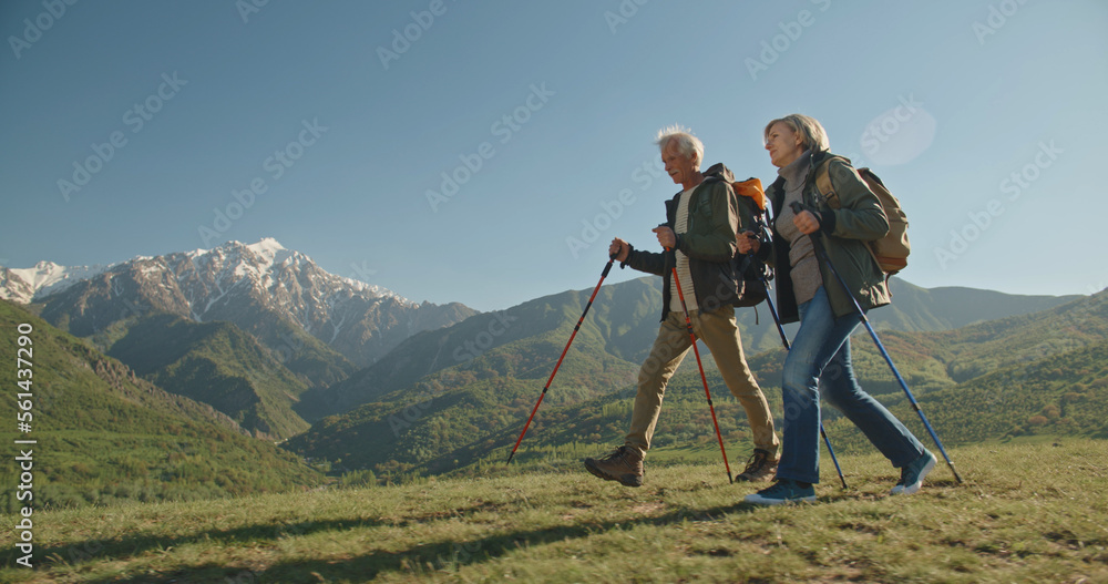 Mature caucasian couple on vacation, having a hike in spring mountains, spending time together after retirement together travelling - tourism, pension concept 