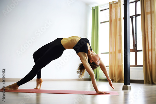 Yoga instructor showing asana in studio on the rug. Mat and a beautiful yoga woman. Morning yoga, yoga practice concept