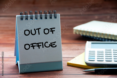 Tableau sur toile Out of office text on calendar desk with notebook, calculator and pen background