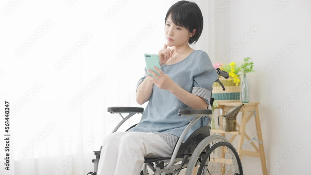 車椅子に座りながらスマートフォンを操作する若い女性 多様性社会イメージ 車椅子に座りながらスマートフォンを操作する若い女性 多様性社会イメージ