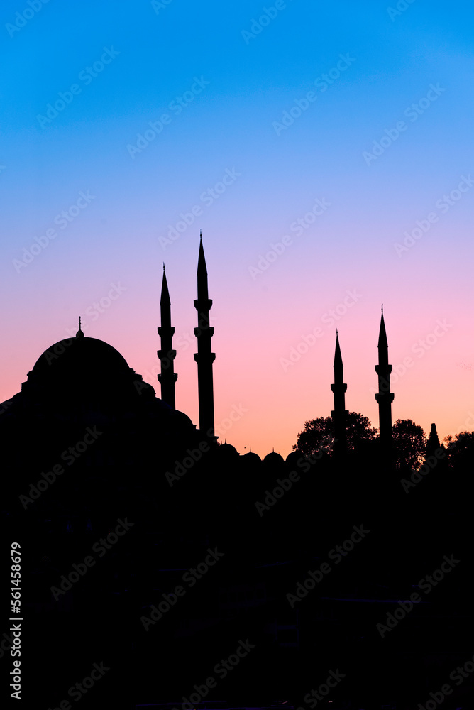 Islamic domes and minarets in silhouette of a Turkish Mosque at sunset on the Istanbul skyline, Turkey.