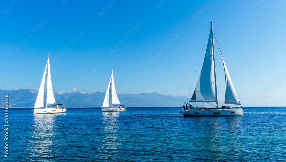 sailing yacht boats with white sails in blue sea , seascape of beautiful ships in sea gulf with mountain coast on background